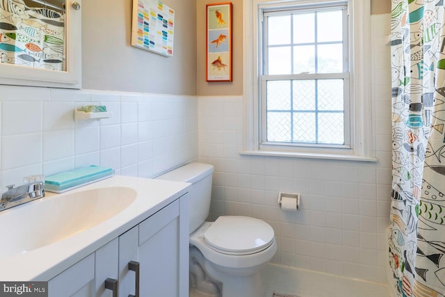 full bathroom with wainscoting, vanity, toilet, a shower with shower curtain, and tile walls