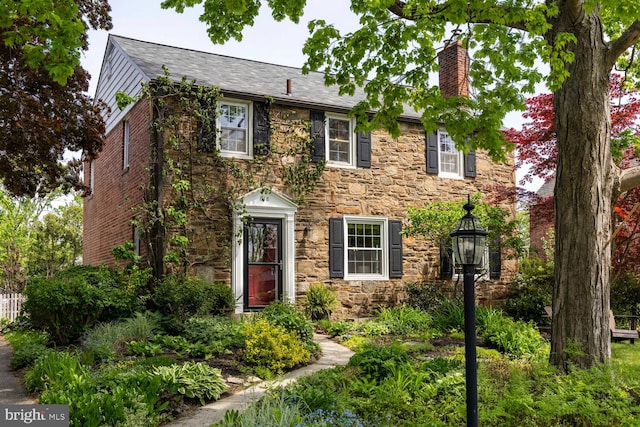 colonial house with a chimney and stone siding