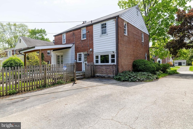 view of front of house featuring brick siding and fence