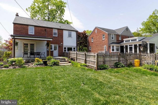 back of house with a lawn, fence, and french doors