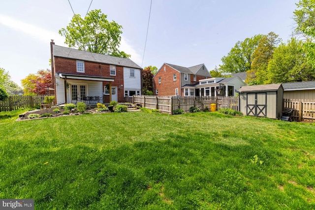rear view of house with a fenced backyard, a storage unit, an outbuilding, and a lawn