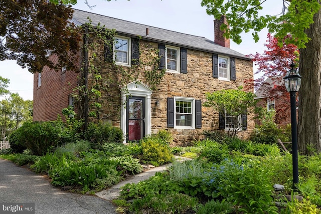 colonial home with a chimney and stone siding