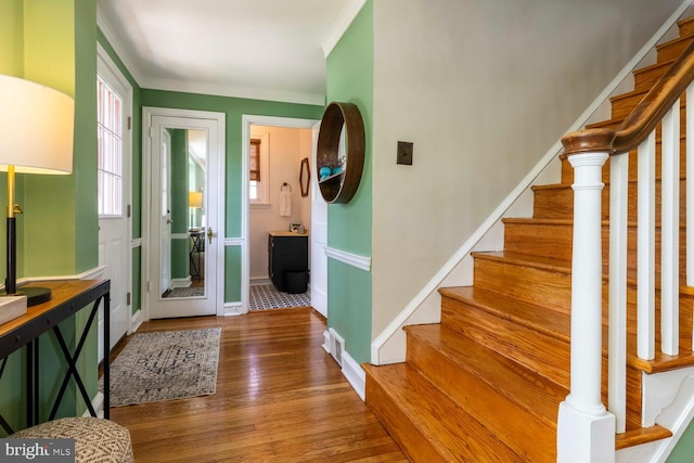 entrance foyer featuring crown molding, baseboards, wood finished floors, and stairway