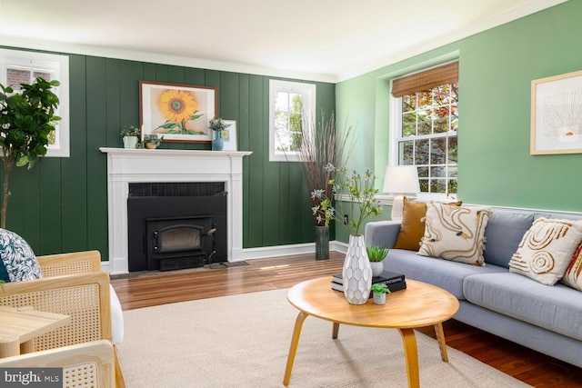 living area with ornamental molding, wood finished floors, and a wood stove