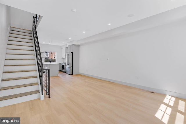 unfurnished living room featuring recessed lighting, visible vents, light wood-type flooring, and stairs