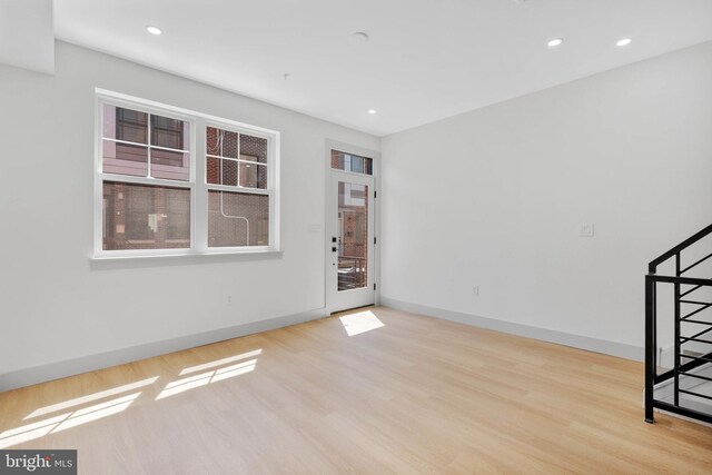 empty room with baseboards, recessed lighting, wood finished floors, and stairs