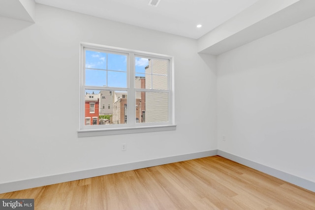 spare room featuring recessed lighting, baseboards, and wood finished floors
