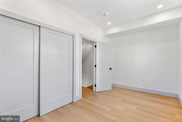 unfurnished bedroom with a closet, recessed lighting, light wood-style flooring, and baseboards