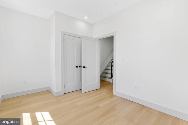 unfurnished bedroom with baseboards, wood finished floors, and a closet