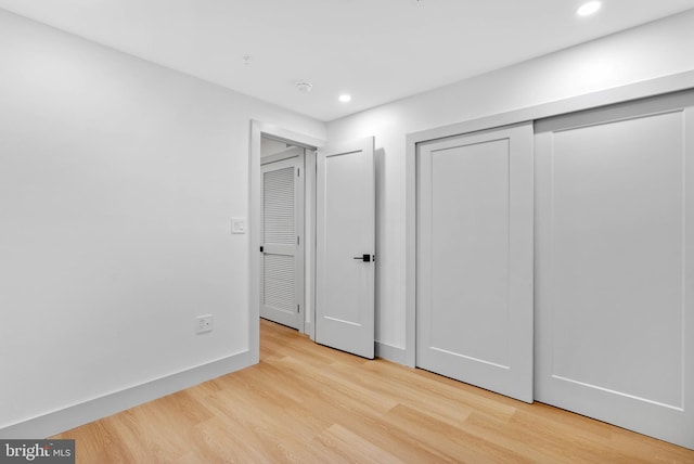 unfurnished bedroom with recessed lighting, baseboards, a closet, and light wood-type flooring