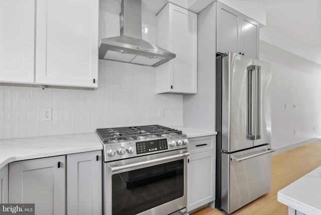 kitchen with light wood-style floors, decorative backsplash, wall chimney range hood, and stainless steel appliances
