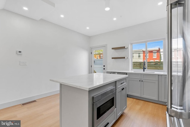kitchen featuring visible vents, light wood finished floors, gray cabinetry, and stainless steel appliances