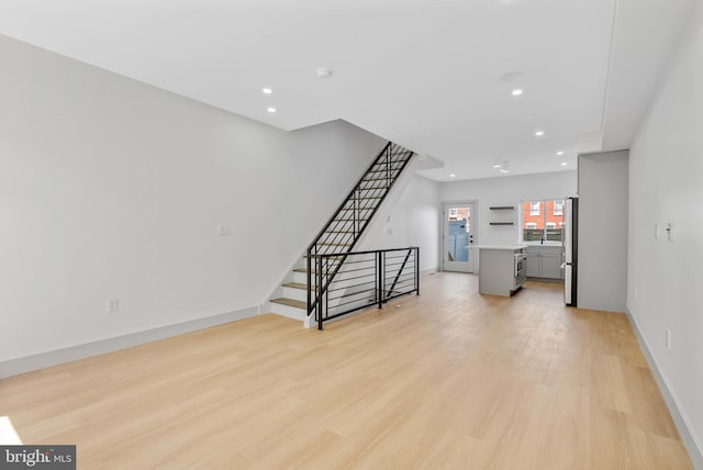 unfurnished living room with recessed lighting, stairway, baseboards, and light wood finished floors