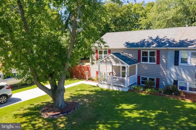 view of front of home with fence, covered porch, and a front lawn