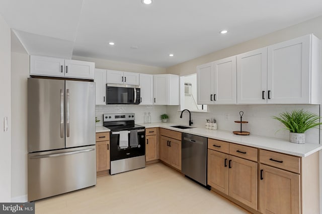 kitchen featuring backsplash, appliances with stainless steel finishes, a sink, light countertops, and recessed lighting