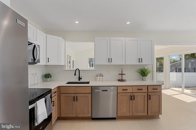 kitchen featuring light countertops, appliances with stainless steel finishes, decorative backsplash, and a sink