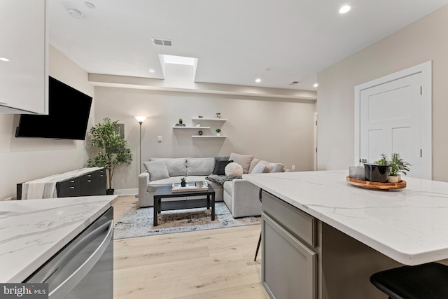818 Kennedy St NW Unit 9, Washington, DC 20011 - kitchen with light wood-type flooring, recessed lighting, light stone countertops, a skylight, and a kitchen island