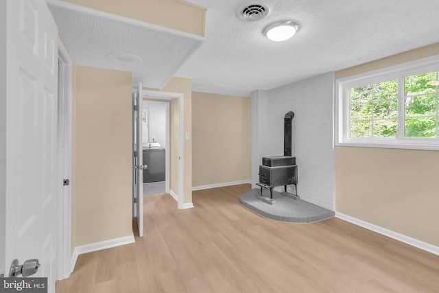 7509 Glade Dr, Fort Washington, MD 20744 - unfurnished living room featuring a wood stove, light wood finished floors, a textured ceiling, and baseboards