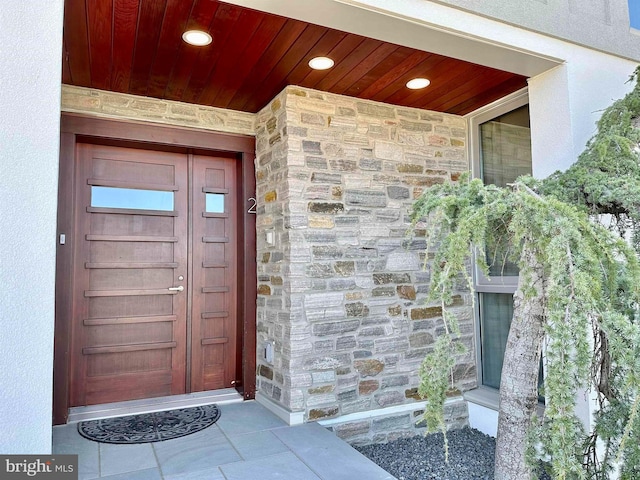view of exterior entry with stucco siding and stone siding