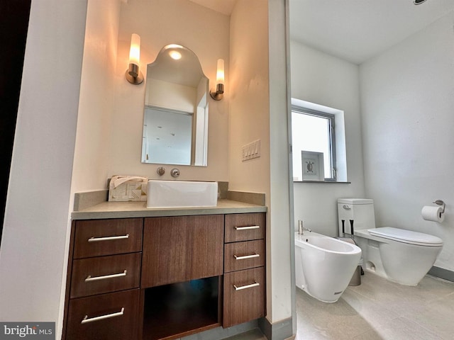 bathroom with baseboards, a bidet, toilet, and vanity