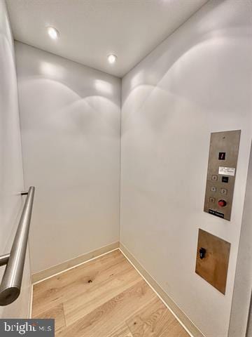 interior space featuring baseboards, recessed lighting, elevator, and wood finished floors