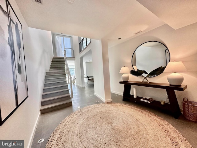 foyer with stairs, baseboards, and visible vents