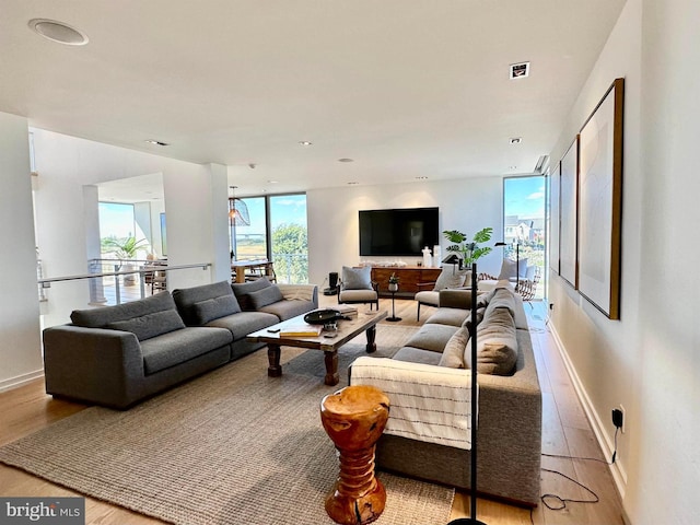 living area with baseboards, light wood-type flooring, and visible vents