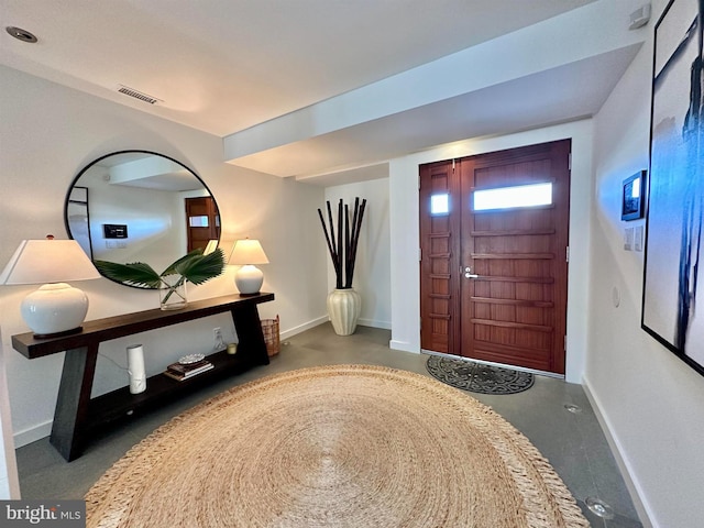 entryway with baseboards, visible vents, and finished concrete flooring