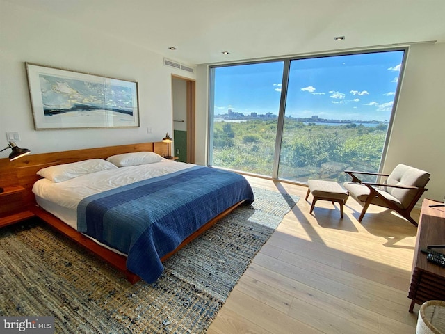 bedroom with floor to ceiling windows, access to exterior, wood finished floors, and visible vents