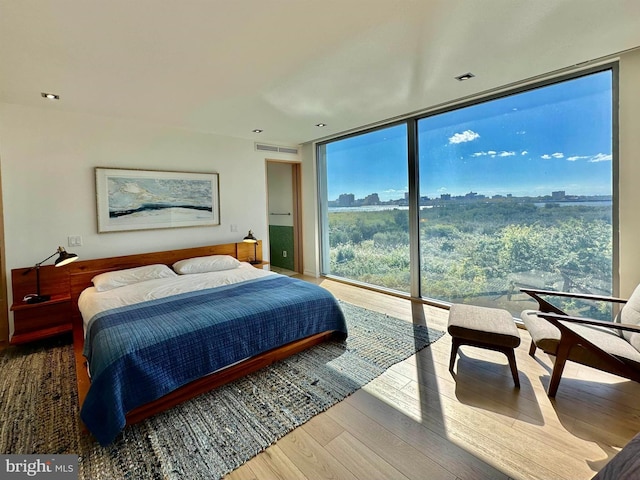 bedroom with a wall of windows, wood finished floors, and visible vents