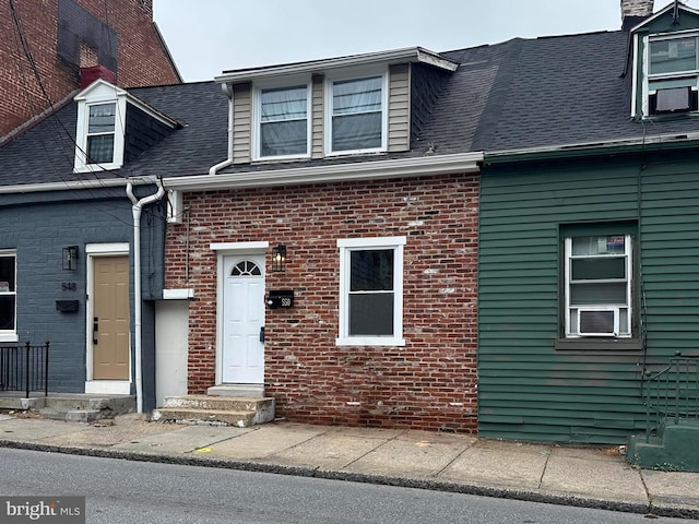 view of front facade featuring brick siding and a shingled roof