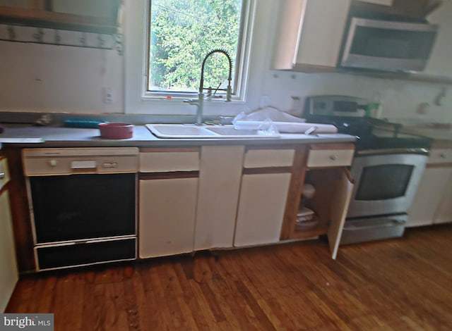 kitchen with white cabinets, stainless steel appliances, a sink, and dark wood-type flooring