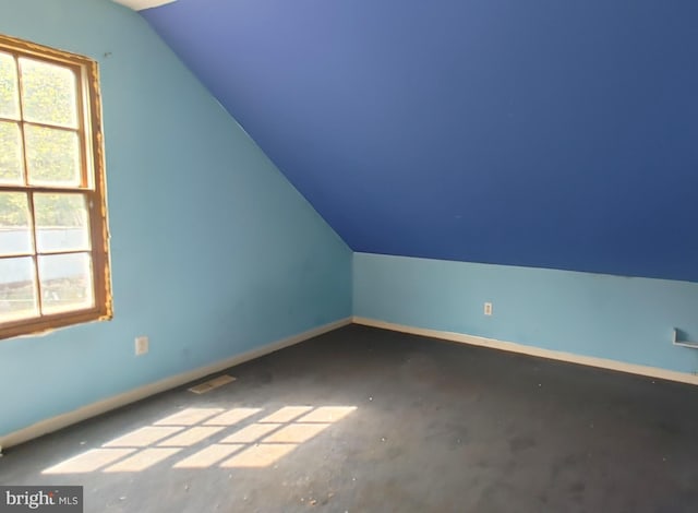 additional living space featuring baseboards, visible vents, and lofted ceiling