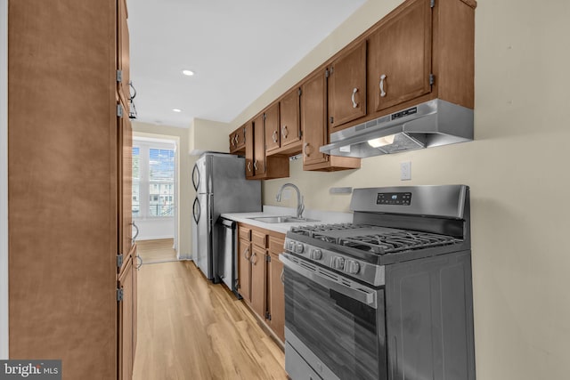 945 Randolph St NW Unit A, Washington, DC 20011 - kitchen featuring appliances with stainless steel finishes, under cabinet range hood, a sink, light wood-type flooring, and light countertops