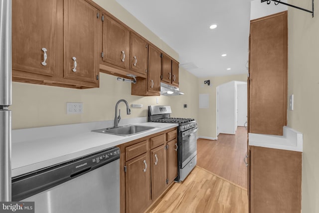 945 Randolph St NW Unit A, Washington, DC 20011 - kitchen with stainless steel appliances, a sink, under cabinet range hood, light wood-style floors, and light countertops