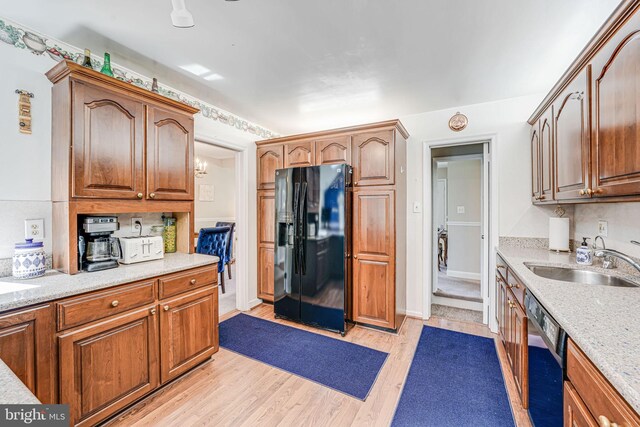 kitchen featuring dishwasher, light wood-type flooring, a sink, and black fridge with ice dispenser