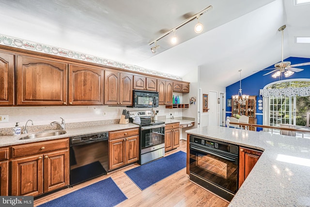 kitchen featuring a sink, light wood-style flooring, ceiling fan with notable chandelier, vaulted ceiling, and black appliances