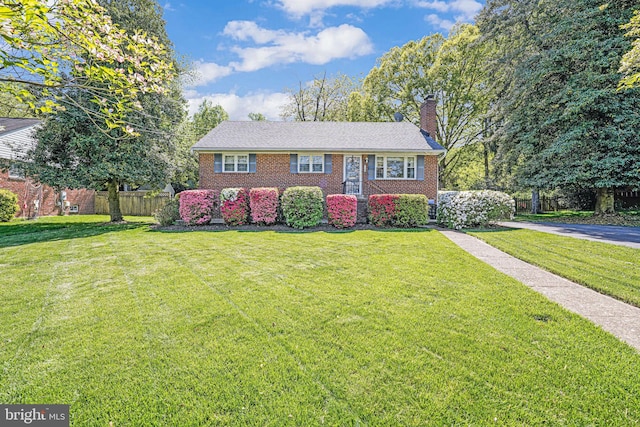 bi-level home featuring fence, a chimney, a front lawn, and brick siding