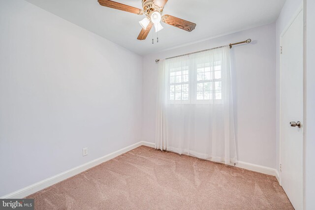 carpeted spare room featuring ceiling fan and baseboards