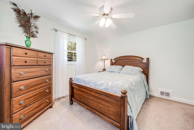 bedroom with light colored carpet, baseboards, visible vents, and ceiling fan