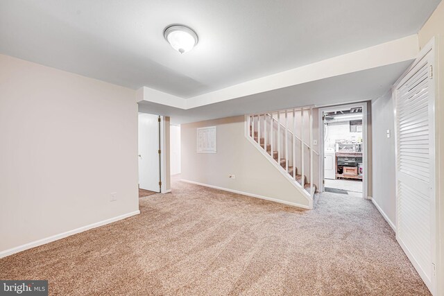 finished basement featuring carpet floors, baseboards, stairs, and washer / clothes dryer