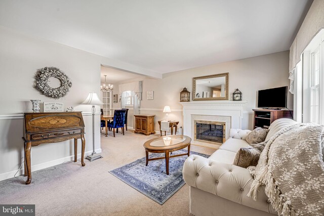 living area featuring baseboards, carpet, a glass covered fireplace, and a chandelier