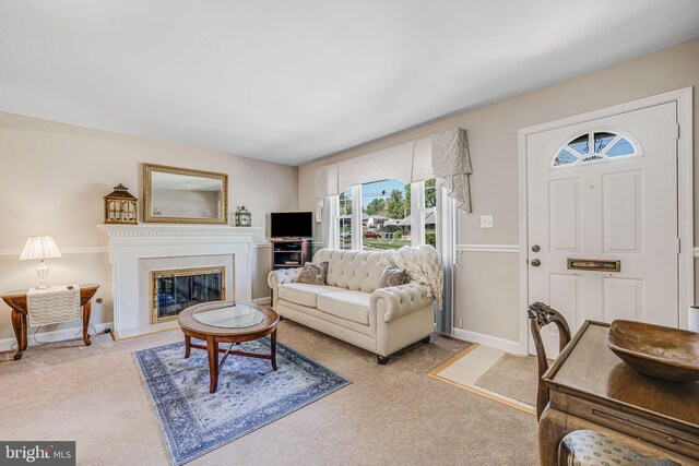 living area featuring carpet flooring, baseboards, and a glass covered fireplace