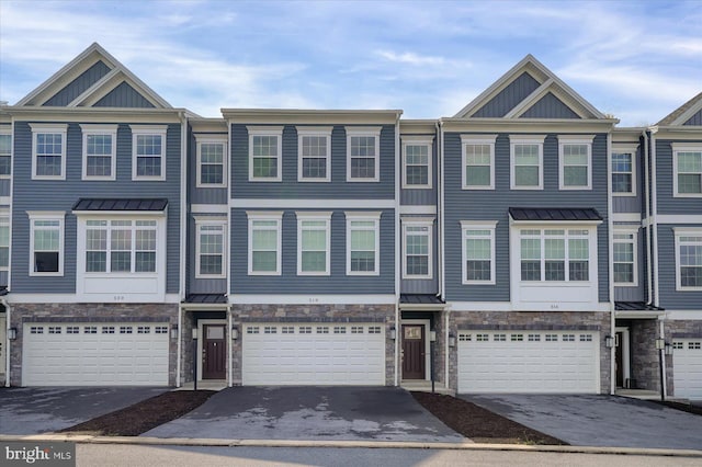 townhome / multi-family property with stone siding, an attached garage, and driveway
