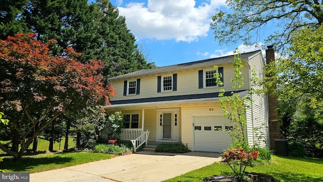 traditional home featuring covered porch, driveway, a chimney, a garage, and a front lawn