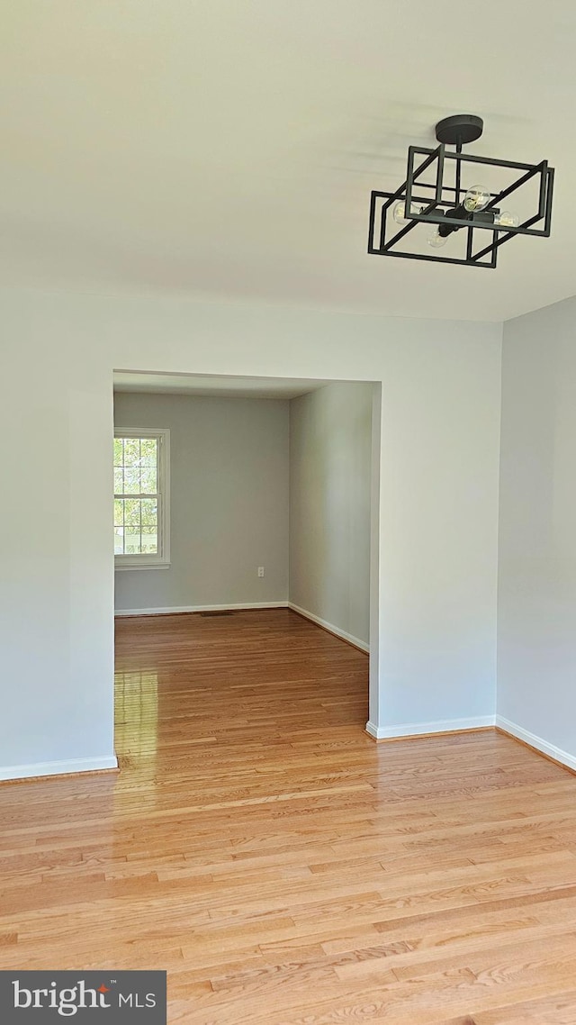 interior space featuring an inviting chandelier, baseboards, and light wood-style flooring