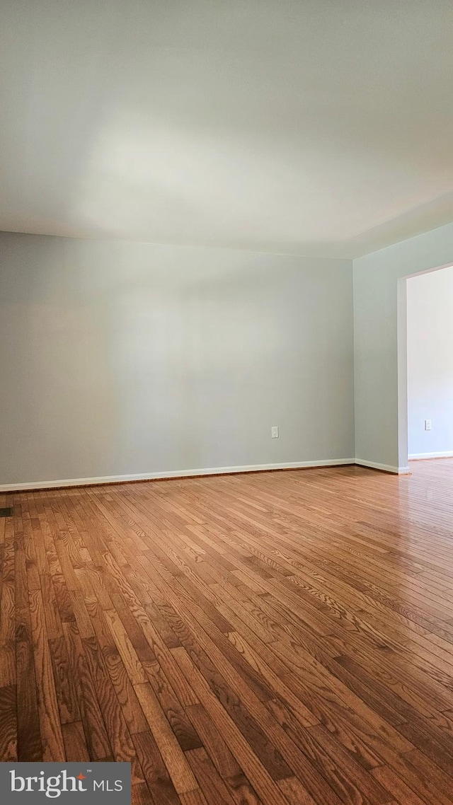 unfurnished room with baseboards and hardwood / wood-style flooring