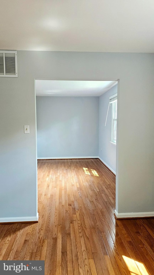 unfurnished room featuring baseboards, visible vents, and wood finished floors