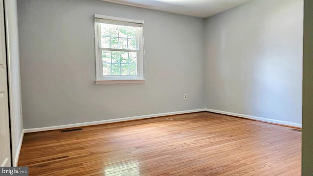 unfurnished room featuring wood-type flooring, baseboards, and visible vents