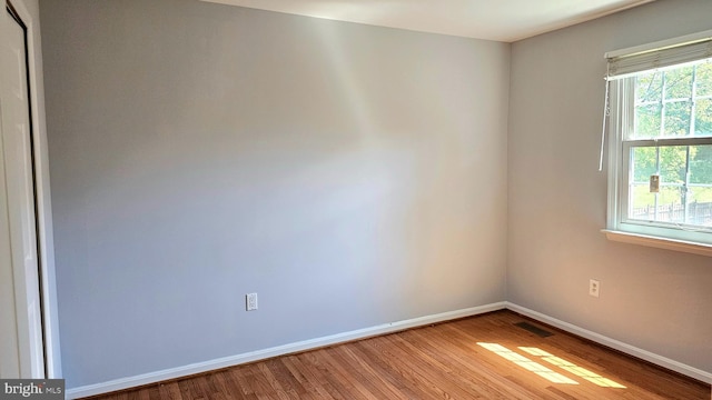 spare room featuring baseboards, wood finished floors, and visible vents